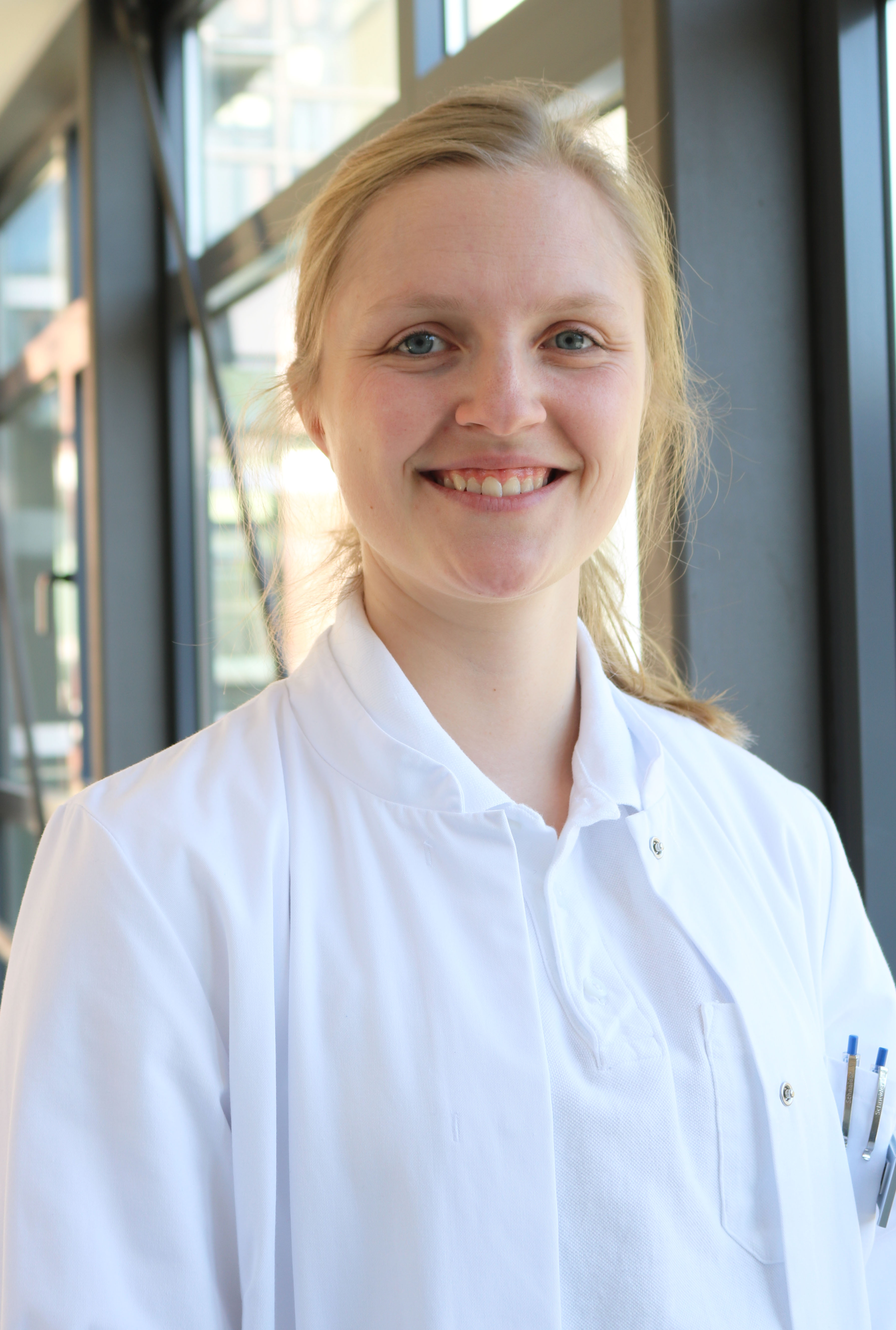 Junge, blonde Frau in weißem Kittel