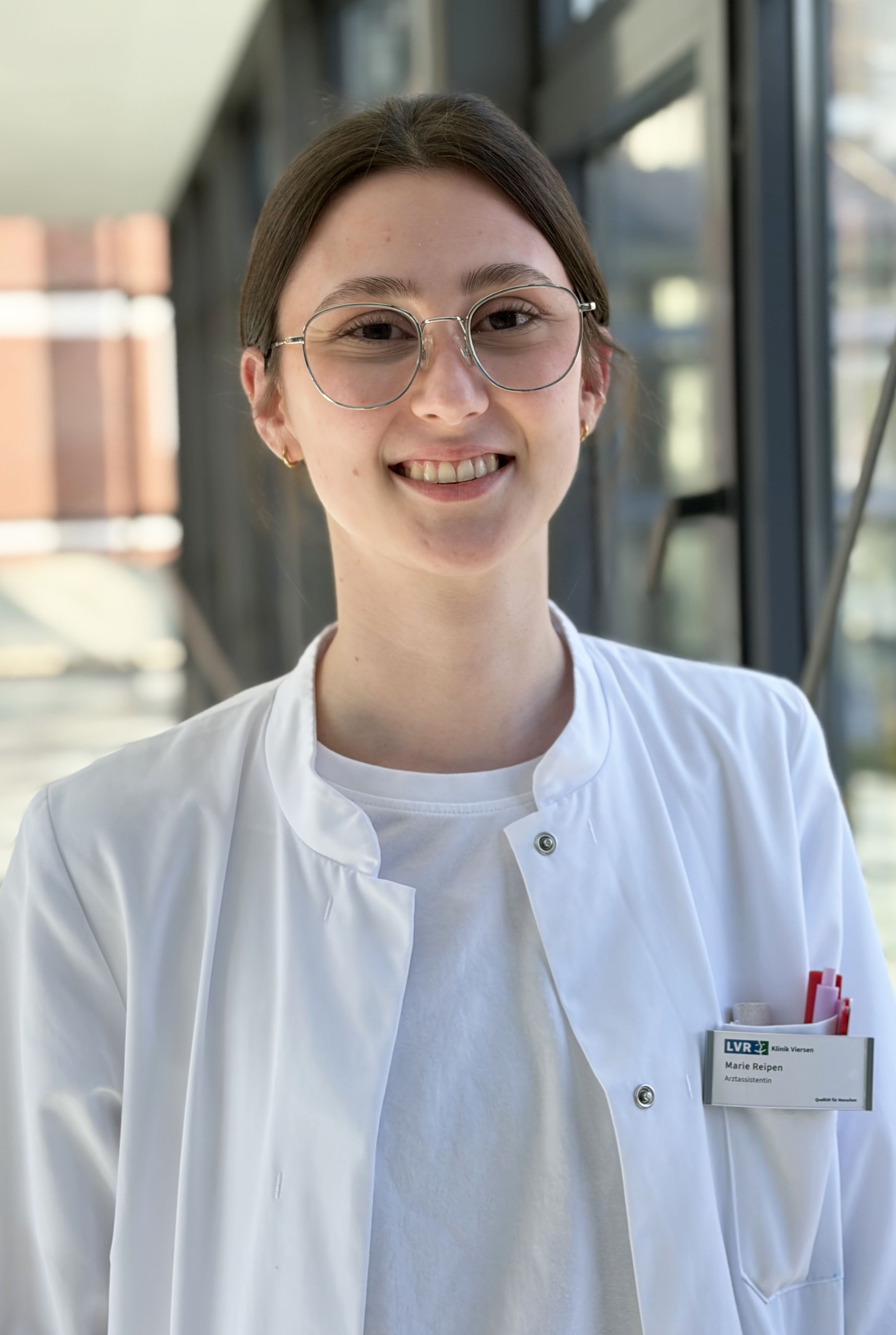 Junge Frau mit Brille im Arztkittel