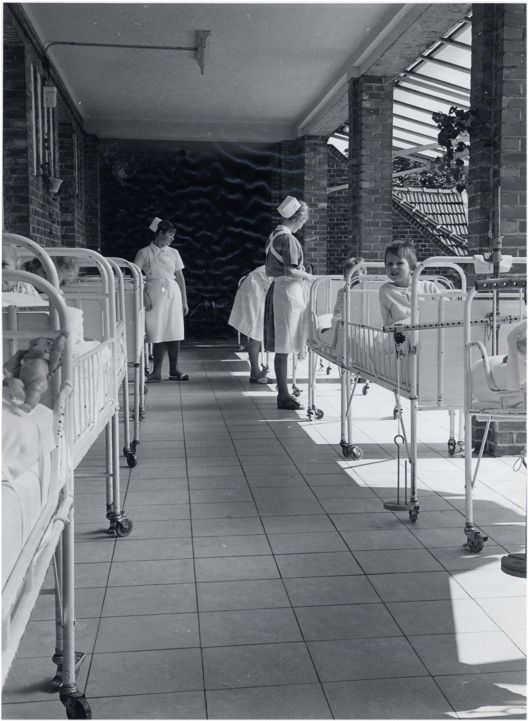 Schwarz-Weiß-Bild des Balkons der Klinik mit Betten und Patient*innen