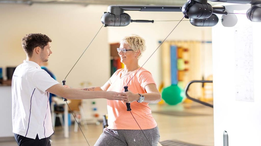 Patientin und Physiotherapeutan einer Kraftmaschine.